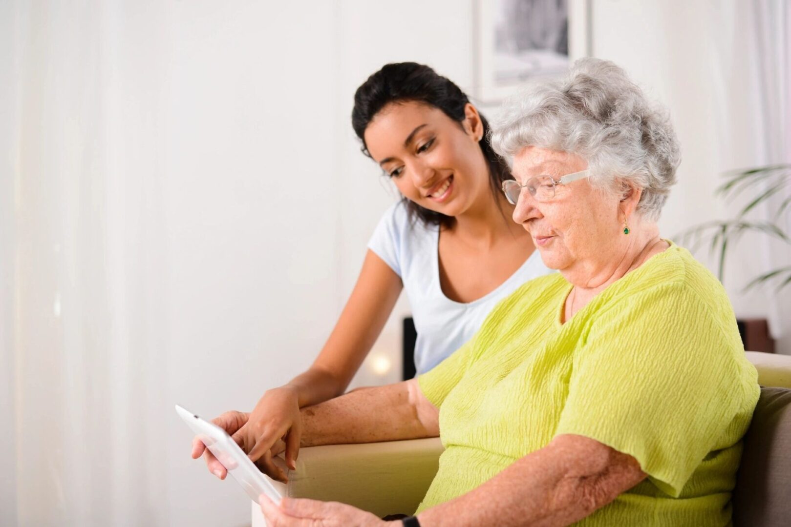 A woman and an older person looking at something on a tablet.